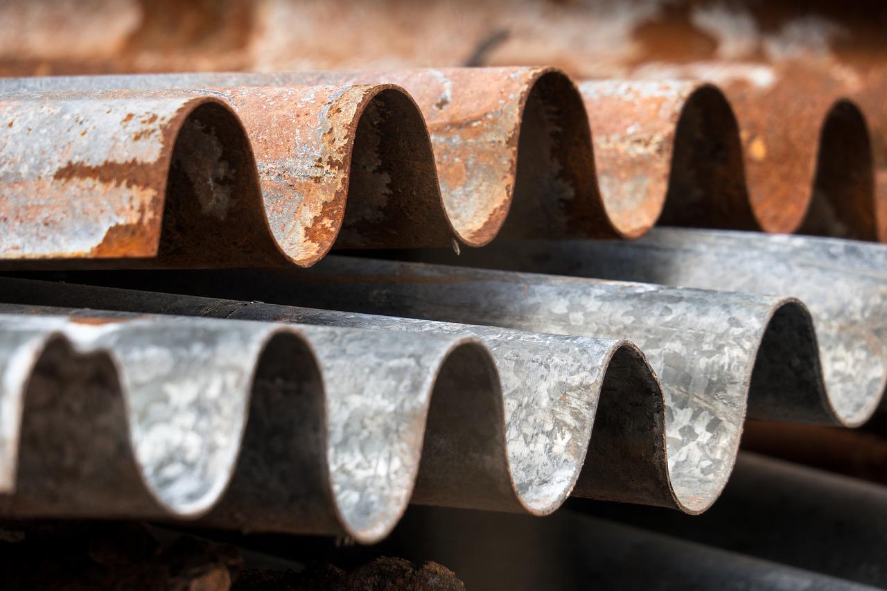 Gestapelde verweerde asbestcement golfplaten met roestbruine aanslag